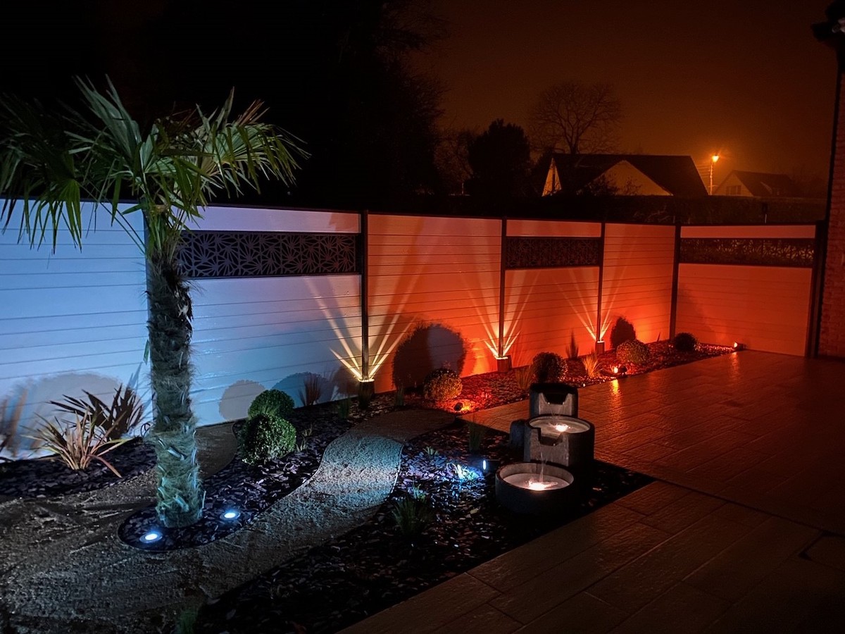 Lavage voiture haute pression : rinçage et mousse Lavage haute pression d'une voiture noire savonneuse sous un ciel bleu, l'eau mousse sur le capot et le pare-chocs.