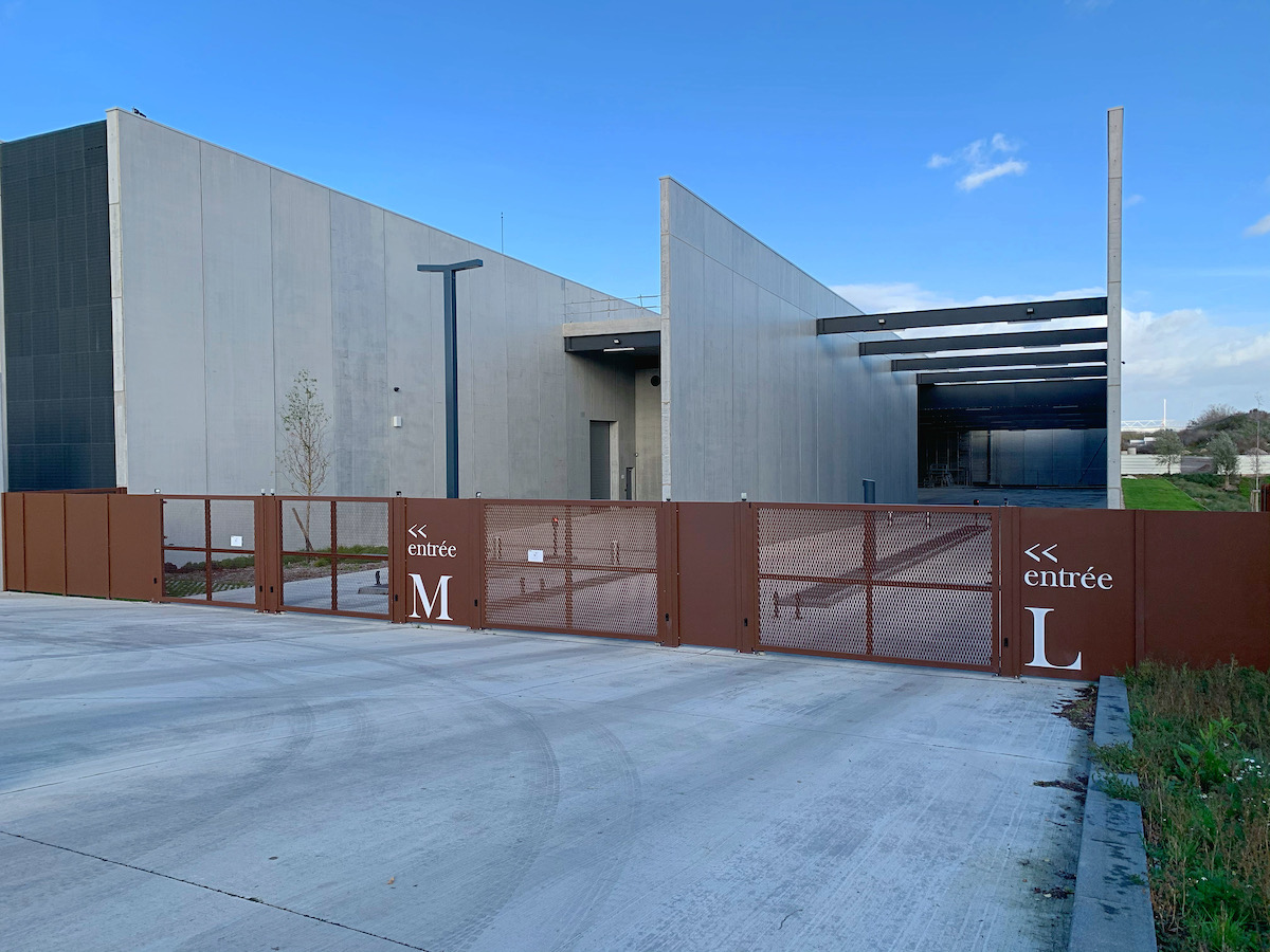 Lavage voiture haute pression : rinçage et mousse Lavage haute pression d'une voiture noire savonneuse sous un ciel bleu, l'eau mousse sur le capot et le pare-chocs.