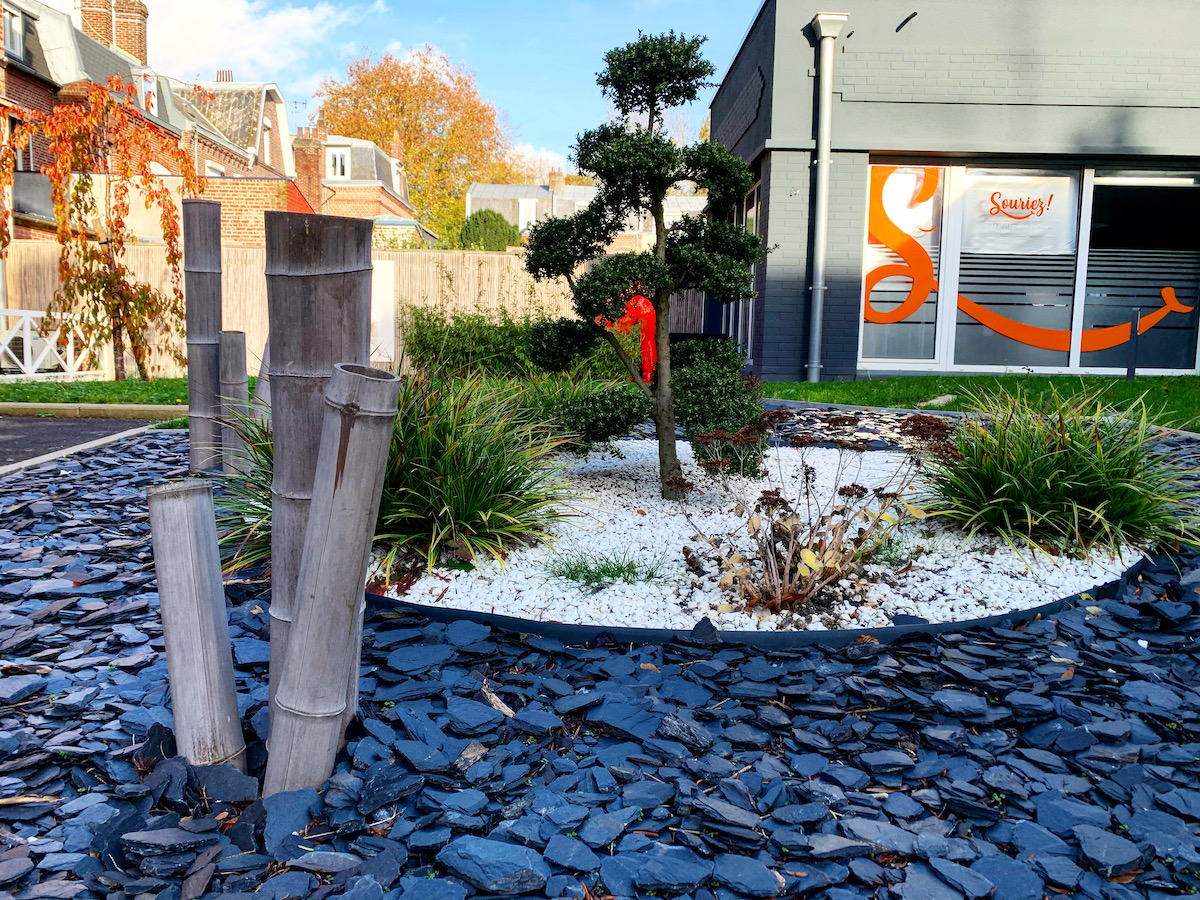 Lavage voiture haute pression : rinçage et mousse Lavage haute pression d'une voiture noire savonneuse sous un ciel bleu, l'eau mousse sur le capot et le pare-chocs.